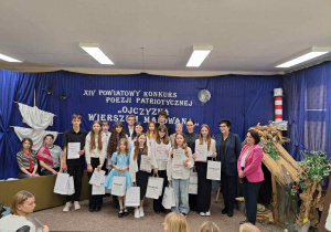 Grupa młodzieży z kobietami stoją na scenie