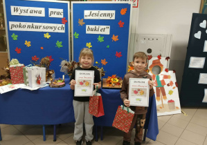 Chłopiec z dziewczynką stoją z dyplomami