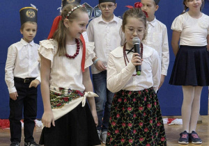 Uśmiechnięte dziewczynki w stroju galowym mówią do mikrofonu