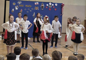 Uśmiechnięte dziewczynki w stroju galowymi tańczą z pomponami