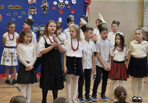 Uśmiechnięte dziewczynki w stroju galowymi i koralach oraz chłopcy w czapkach górnika