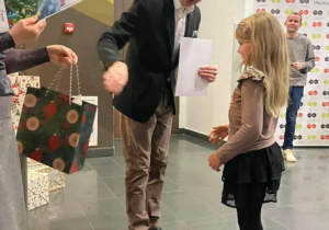 Mężczyzna wręcza nagrodę dziewczynce.