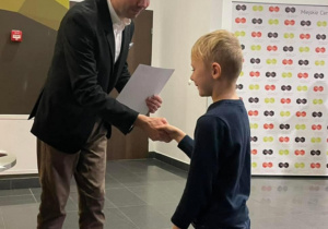 Mężczyzna wręcza nagrodę chłopcu