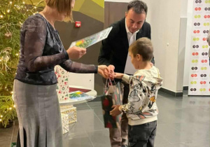 Mężczyzna z kobietą wręczają nagrodę chłopcu