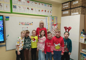 Radosne dzieci z panią ubrane w świąteczne swetry