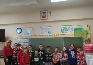 Radosne dzieci z panią ubrane w świąteczne swetry