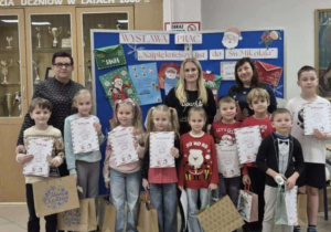 Uśmiechnięte dzieci z kobietami trzymają dyplomy