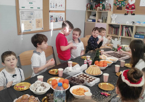 Uśmiechnięte dzieci siedzą przy stole wigilijnym w klasie 2c