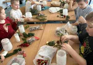 uśmiechnięte dzieci siedzą przy stole z dekoracjami świątecznymi