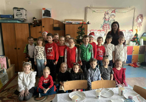 Uśmiechnięte dzieci z panią pozują do zdjęcia grupowego