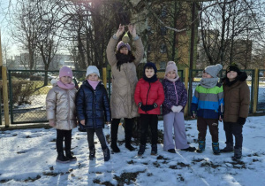 Pani wiesza na drzewie karmę dla ptaków