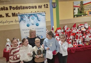 Pani z dziećmi, które trzymają dyplom i statuetkę z napisem "Regionalny festiwal kolęd i pastorałek"