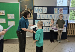 Kobieta wręcza chłopcu dyplom