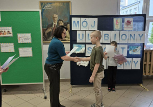 Kobieta wręcza chłopcu dyplom