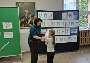 Kobieta wręcza dziewczynce dyplom