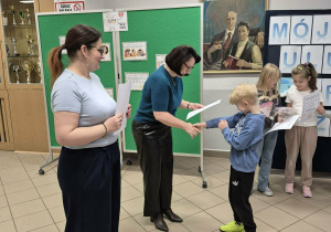 Kobieta, a obok druga kobieta wręcza chłopcu dyplom