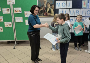 Kobieta wręcza chłopcu dyplom