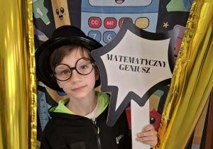 Dziecko w czarnym kapeluszu pozuje do zdjęcia w ramce