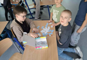 Chłopcy przy stoliku rozwiązują zagadki
