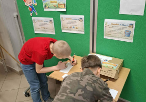 Chłopcy przy stoliku rozwiązują zagadki