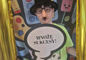 Dziecko w czarnym kapeluszu pozuje do zdjęcia w ramce