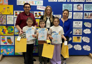 Dzieci z kobietami na tle rysunków kolorowych skarpetek.