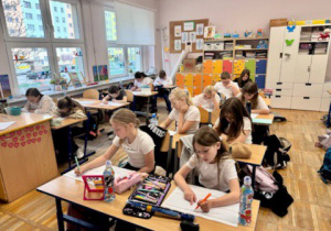 Dzieci siedzą w ławkach i rozwiązują test