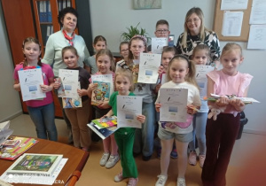 Radosne dzieci z kobietami prezentują dyplomy u nagrody