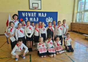 Dzieci ubrane na galowo z kobietą na tle napisu: Wiwat maj, 3 maj"