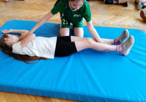 Dziewczynka układa w pozycji bezpiecznej dziecko leżące na materacu