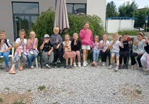 Radosne dzieci siedzą na krzesłach i jedzą lody