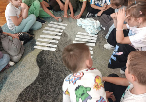 dzieci siedzą na dywanie w kole