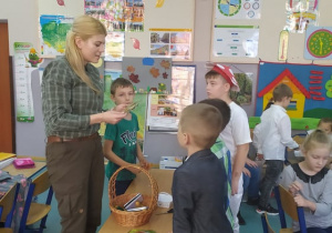 Dzieci na spotkaniu z panią leśnik przy stoliku oglądają zdjęcia grzybów