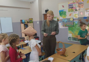 dziewczynki na spotkaniu z panią leśnik przy stoliku oglądają zdjęcia grzybów