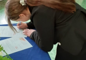 dziewczyna podpisuje pismo